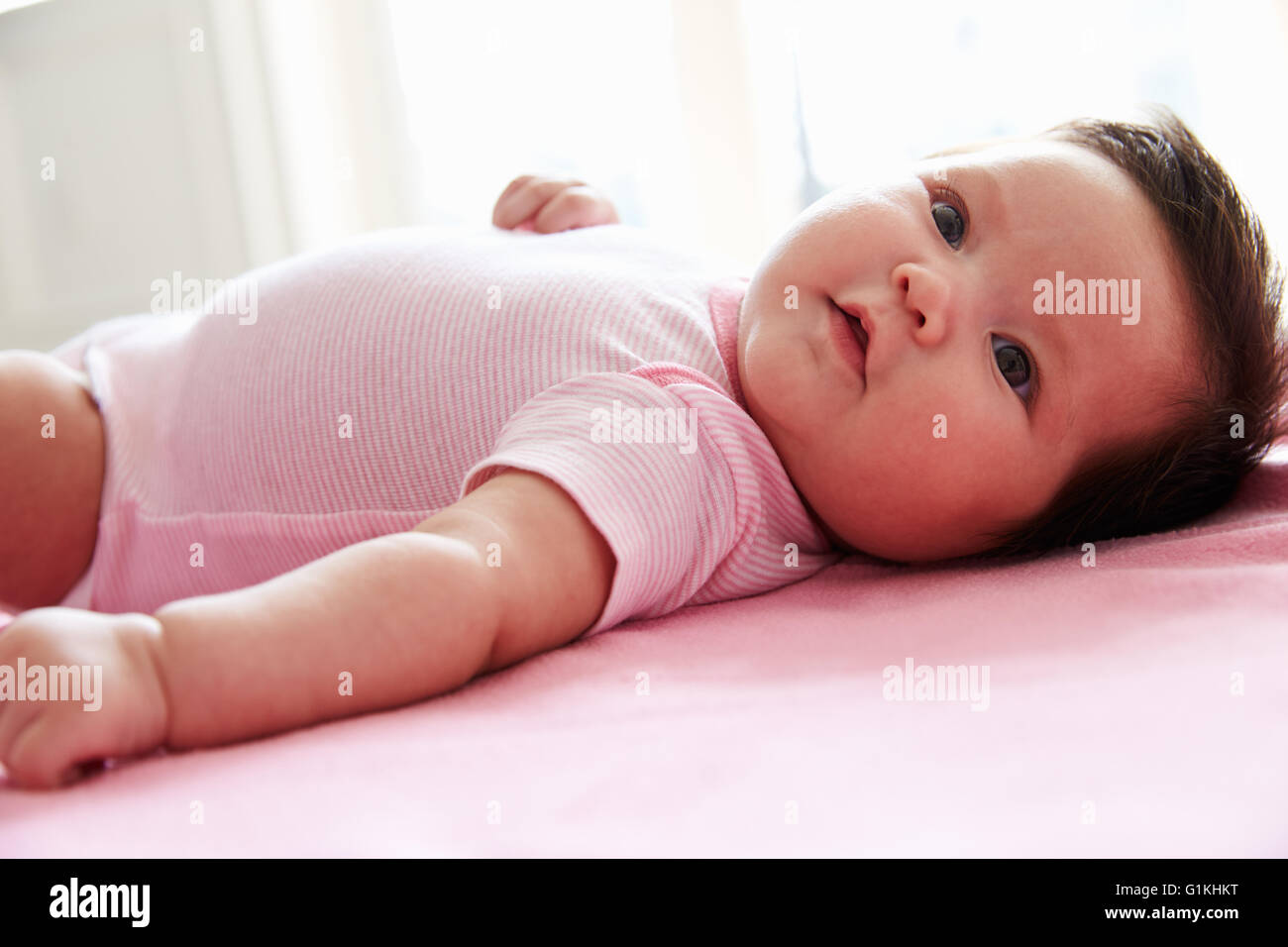 Niedliche Babymädchen rosa Decke auflegen Stockfoto