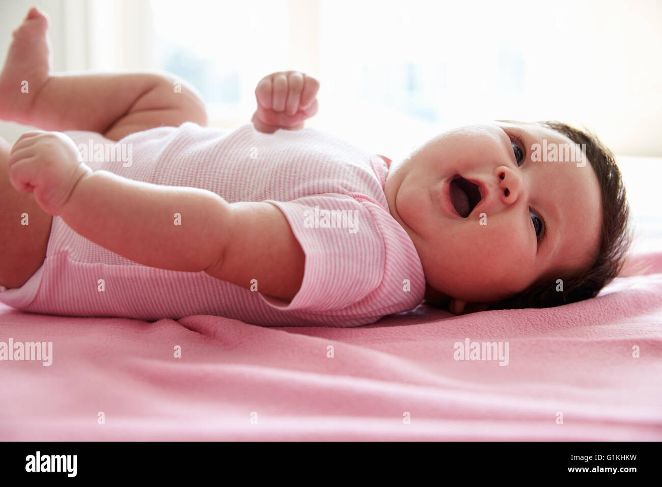 Niedliche Babymädchen rosa Decke auflegen Stockfoto