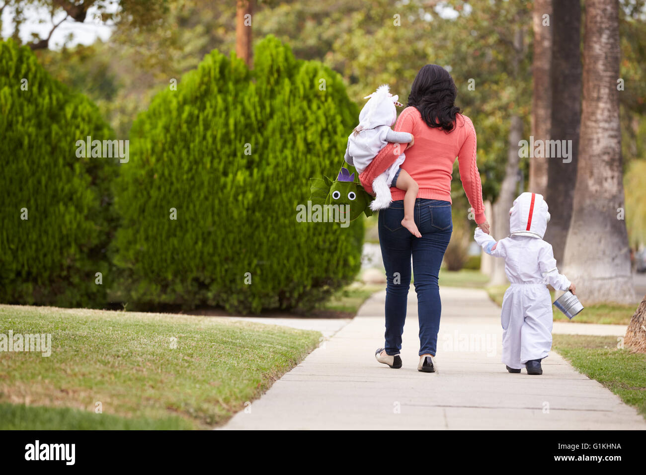 Eltern nehmen Kinder Süßes oder Saures zu Halloween Stockfoto