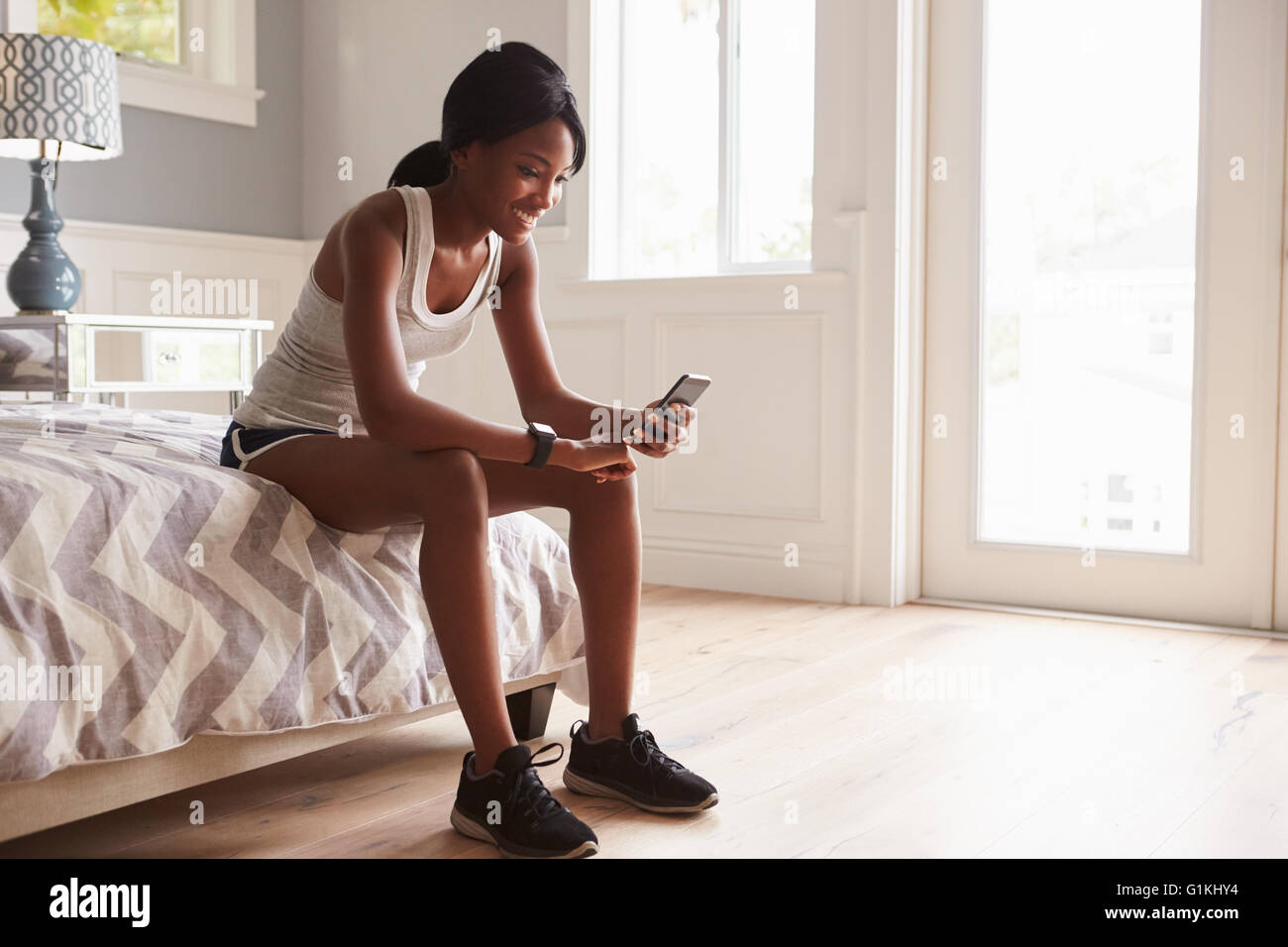 Junge schwarze Frau bereit für Übung, Überprüfung smartphone Stockfoto