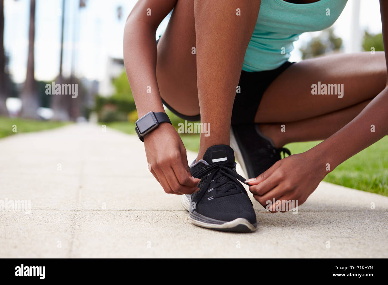 Junge schwarze Frau binden Sportschuhe auf der Straße Stockfoto