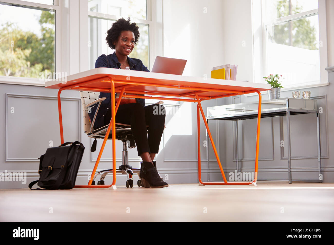 Junge schwarze Frau sitzt an einem Schreibtisch mit einem Laptopcomputer Stockfoto