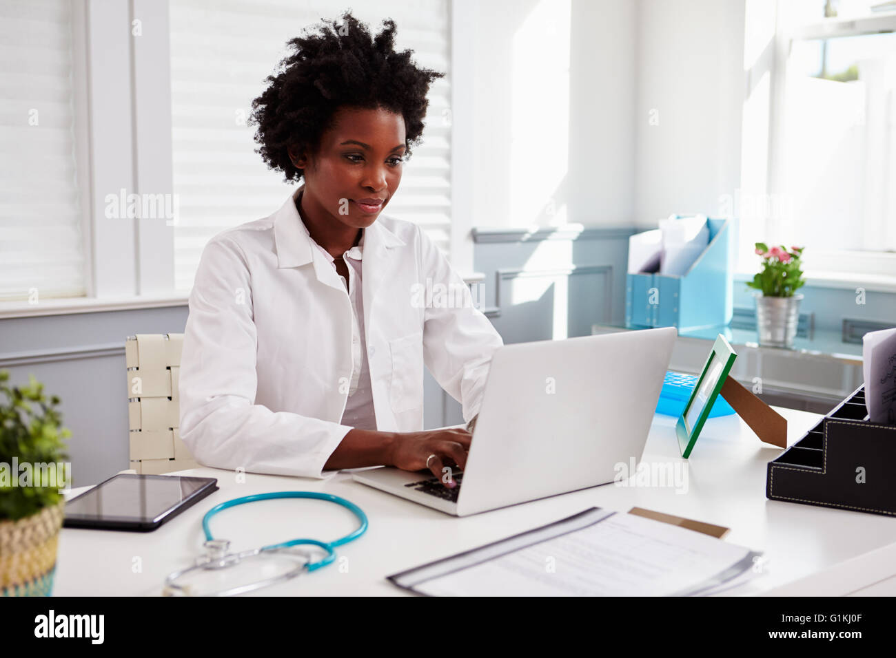 Schwarze weibliche Arzt trägt weißen Kittel bei der Arbeit in einem Büro Stockfoto