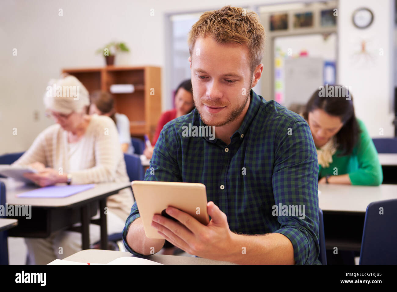 Junger Mann mit Tablet-Computer bei einer Erwachsenenbildung-Klasse Stockfoto