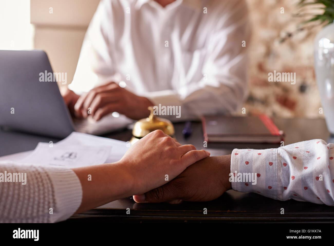 Multi-ethnischen paar halten Hände im Hotel Einchecken Schreibtisch, detail Stockfoto