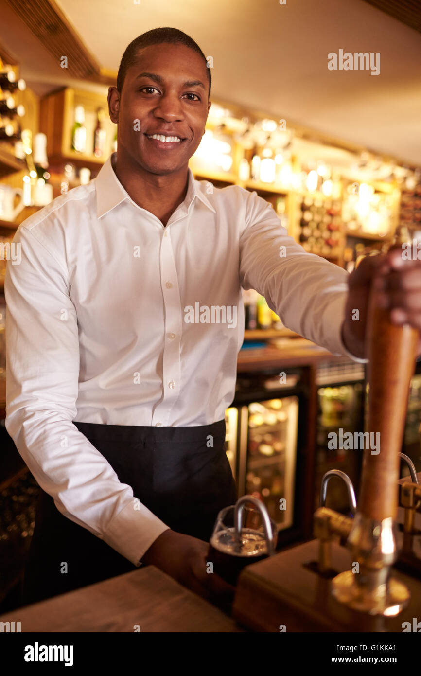 Ein junger schwarzer Mann hinter einer Bar arbeiten sieht, Kamera Stockfoto