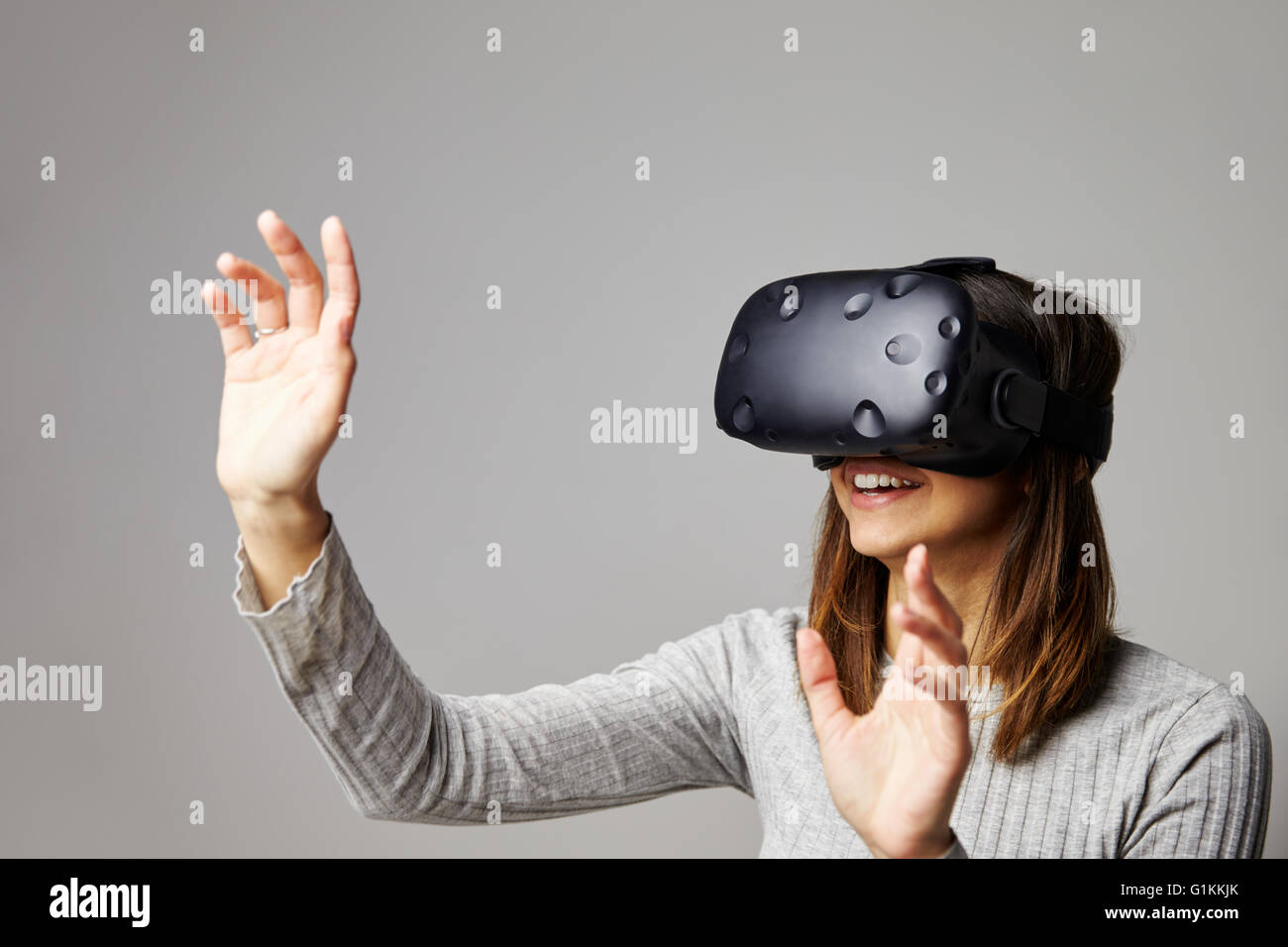 Frau sitzt auf dem Sofa zu Hause tragen Virtual-Reality-Kopfhörer Stockfoto