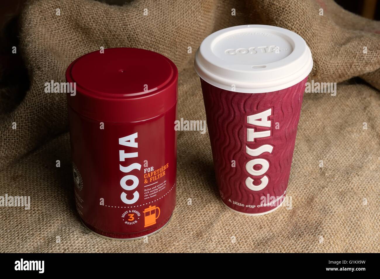 Eine Dose gerösteter und gemahlener Kaffee von Costa und eine Tasse Kaffee zum mitnehmen auf eine hessische Hintergrund. Stockfoto