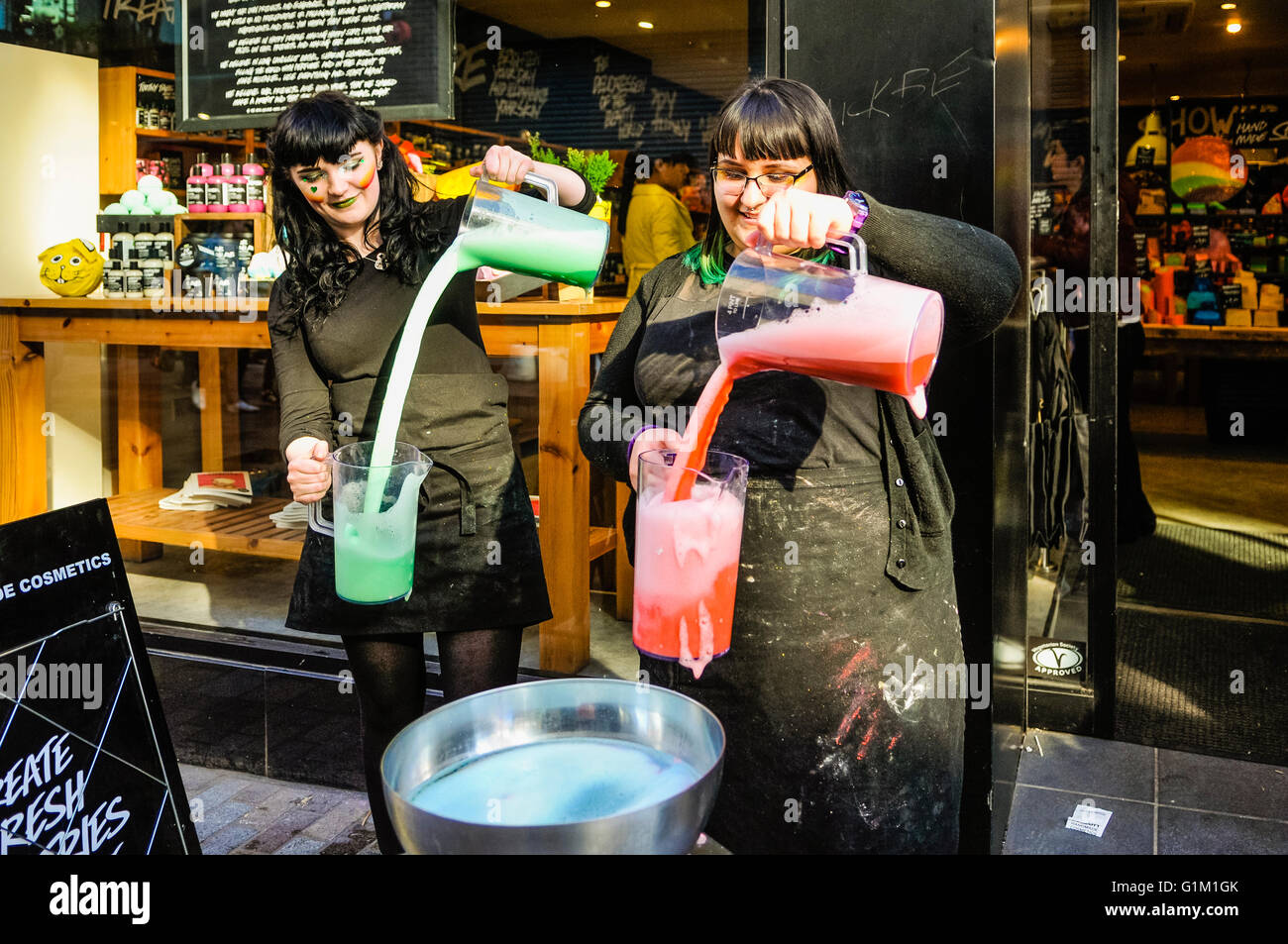 Zwei Mitarbeiterinnen und Mitarbeiter mischen Bad Kosmetik vor einem üppigen Geschäft. Stockfoto