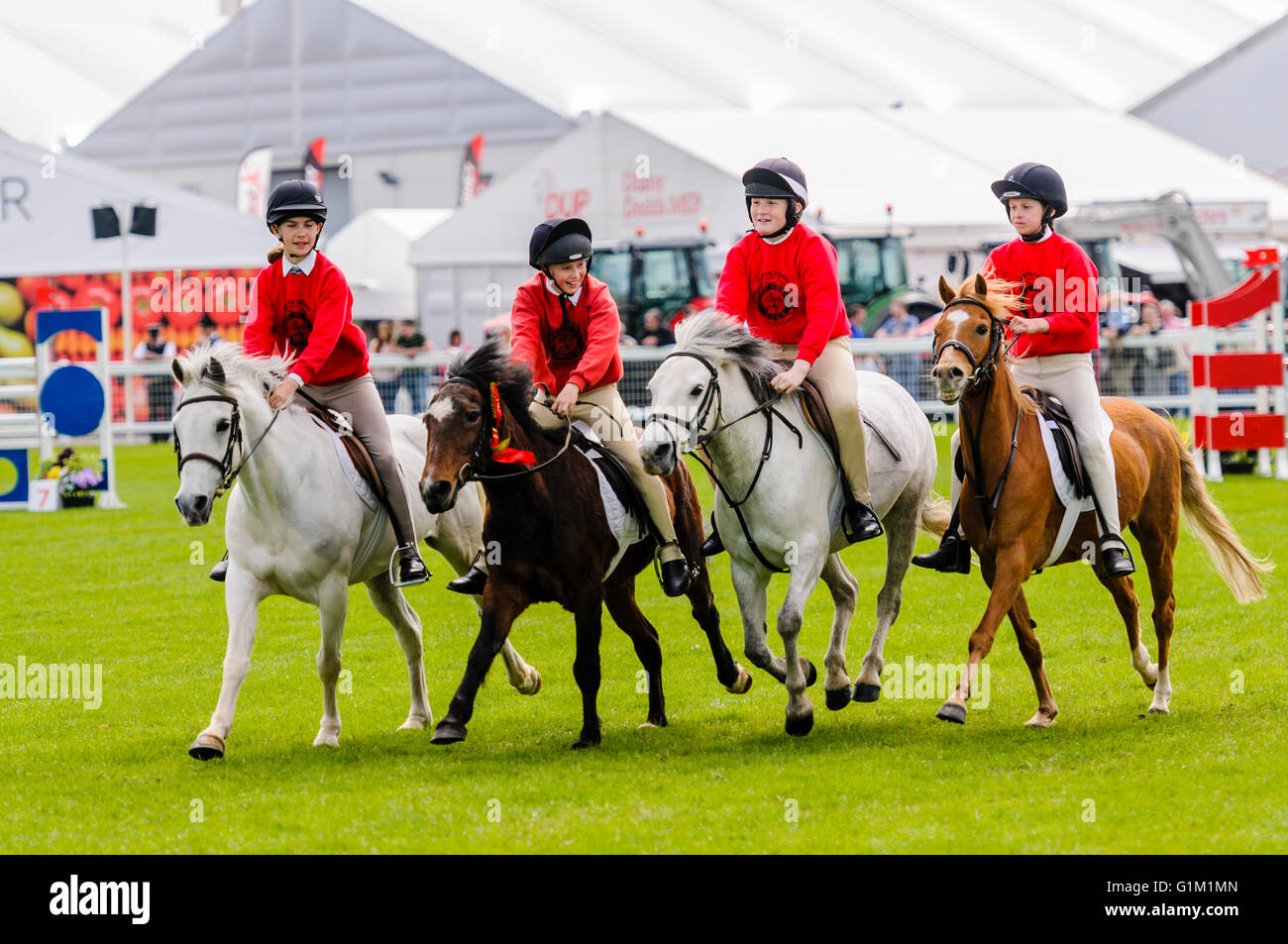 Junge Mädchen aus einem Pony-Club-Rennen um einen Showjumping-Ring Stockfoto