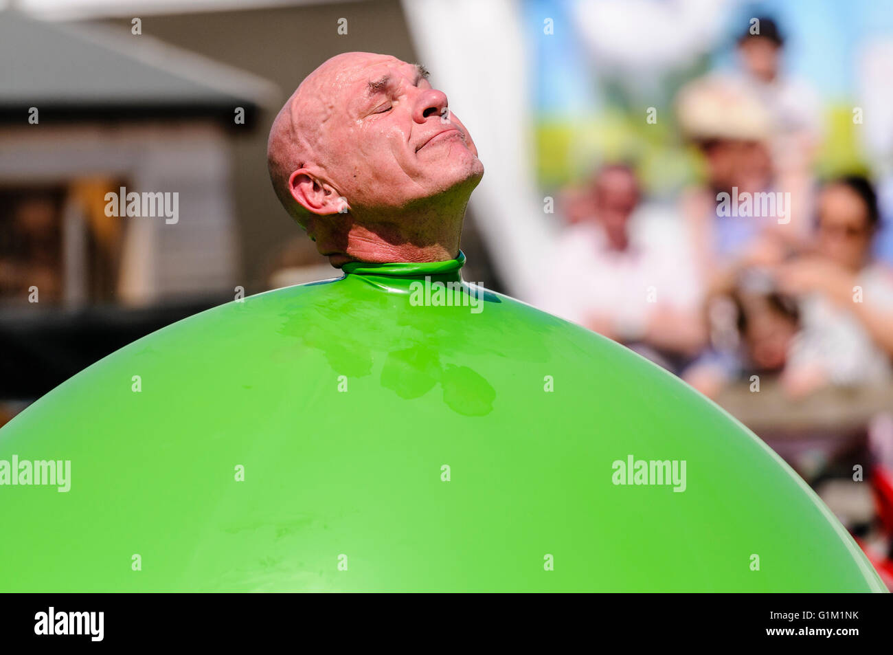 Ein Kinder Darsteller schiebt seinen Kopf aus einem großen grünen aufblasbarer Ballon. Stockfoto