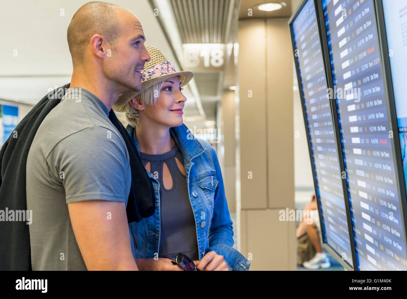 Kaukasische paar lesen Ankünfte und Abflüge am Flughafen Stockfoto
