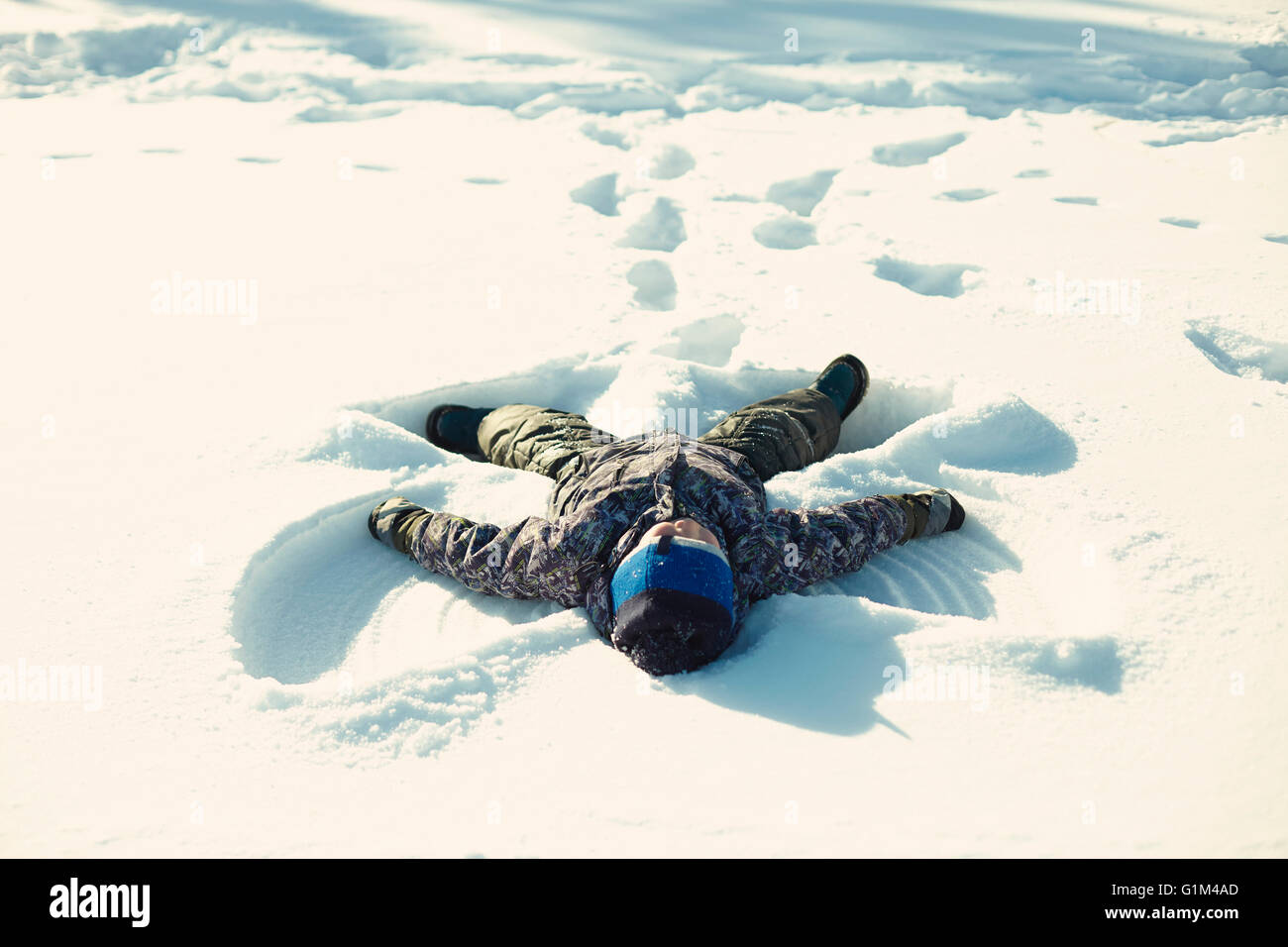 Kaukasische junge machen Schnee-Engel Stockfoto