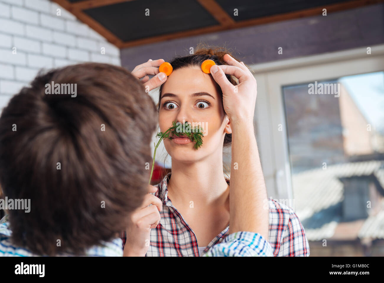 Verspielte junge Paar Spaß haben und machen lustige Gesicht auf dem Küchentisch Stockfoto