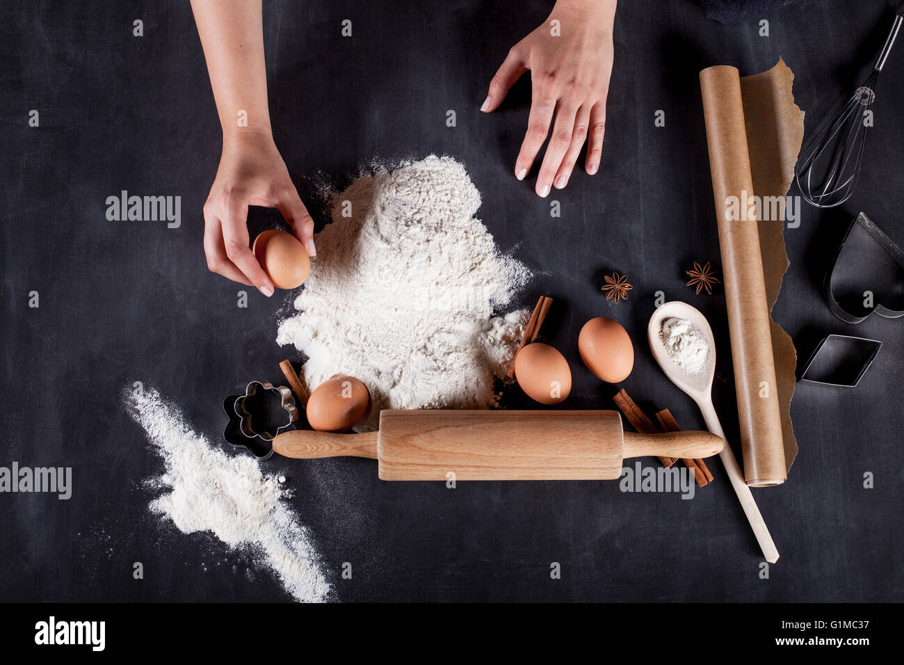 Zutaten wie Eiern, Mehl, Zimt, Anis, Nudelholz, Papier auf Tafel Stockfoto