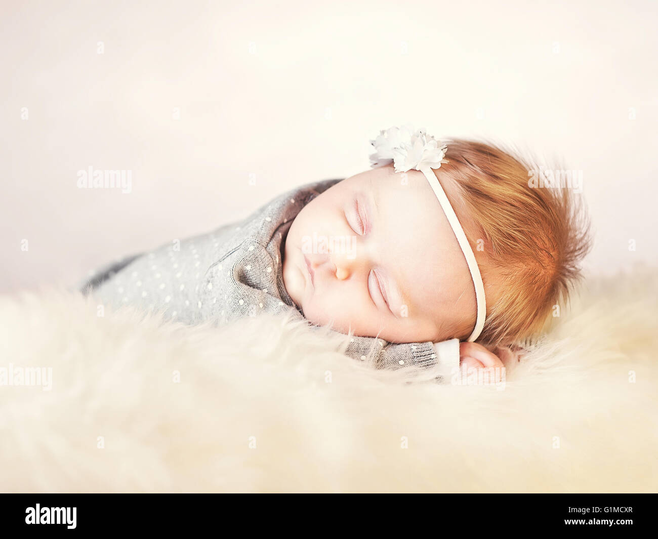 femal Baby auf klassisch weißem Fell schlafen Stockfoto