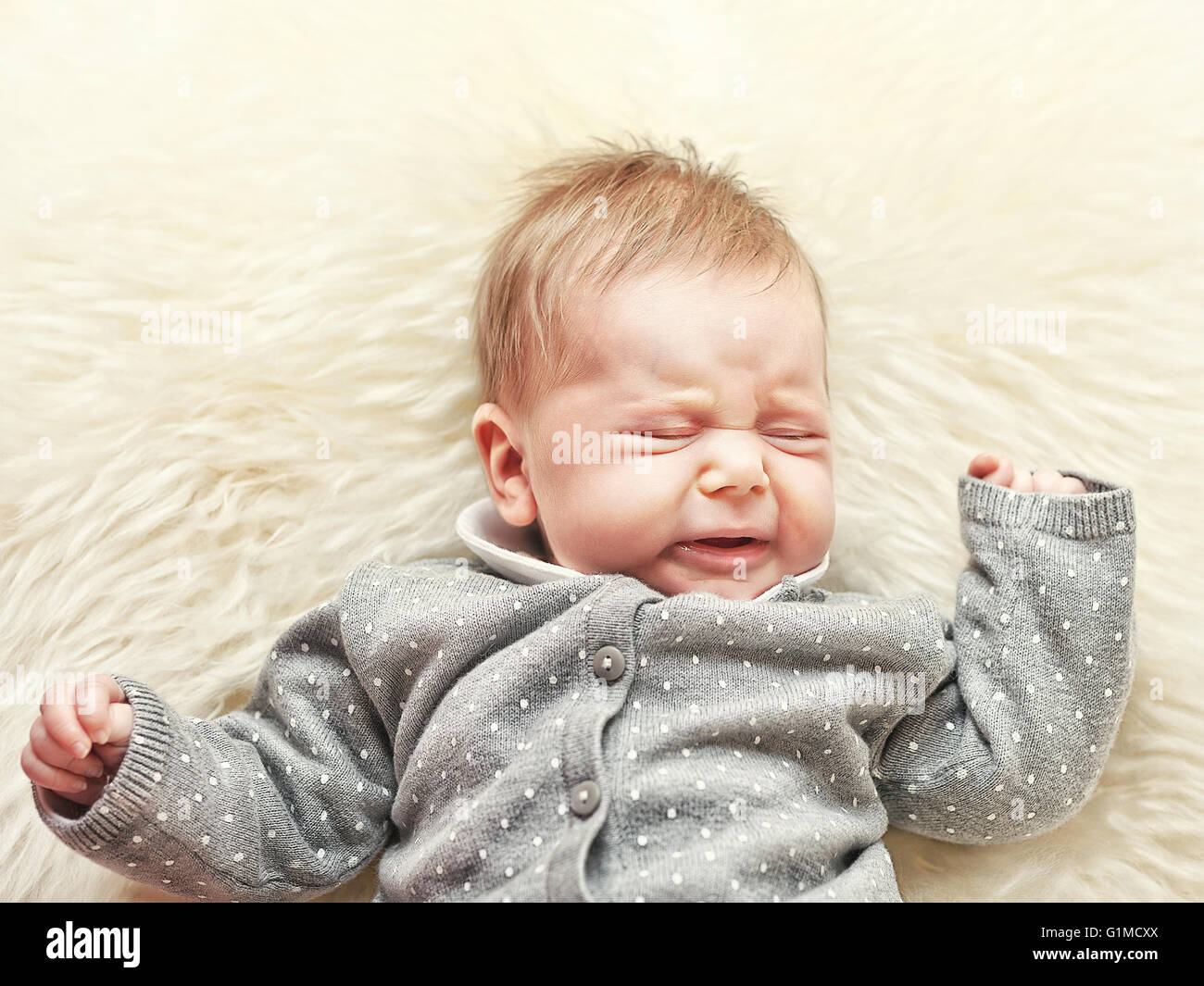 kleines Baby weinte auf klassisches weißes Fell Stockfoto