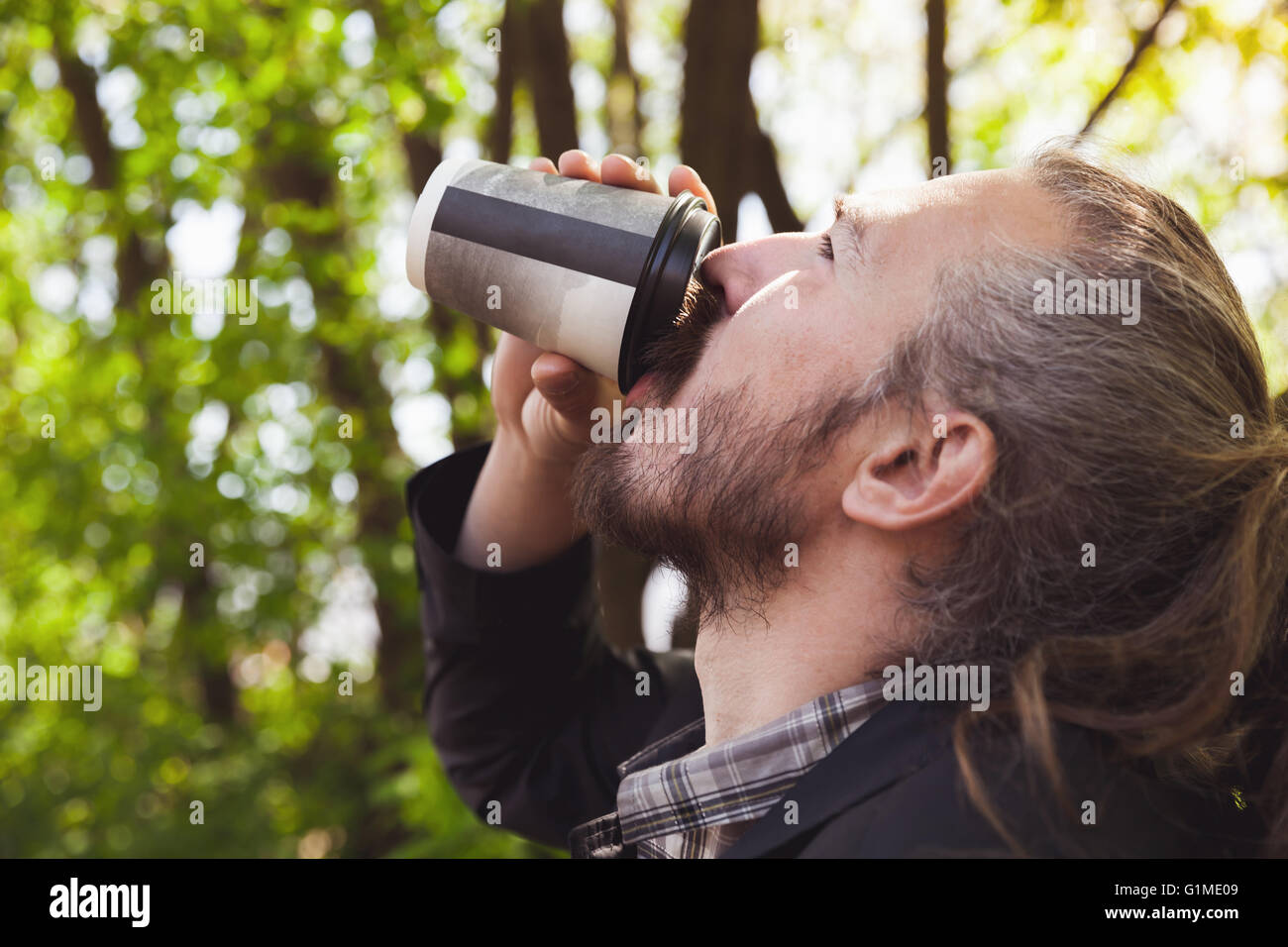 Asiatische bärtige Kaffeetrinken aus Pappbecher im Sommerpark, outdoor Closeup Profilbildnis mit selektiven Fokus Stockfoto