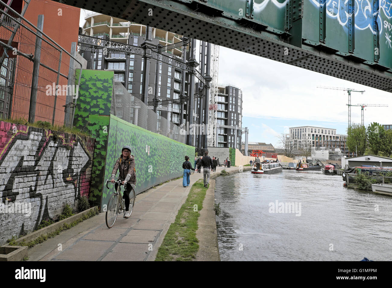 Radsportler auf Treidelpfad entlang Regents Canal vorbei Gasbehälter Neubauwohnungen in Kings Cross London UK KATHY DEWITT Stockfoto