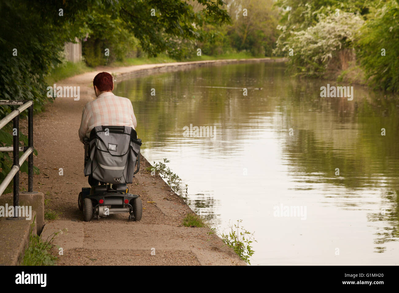 Einem behinderten Menschen mit einer Behinderung-Roller auf dem Treidelpfad, Canal die Grand Union in Warwick, Warwickshire, Großbritannien Stockfoto
