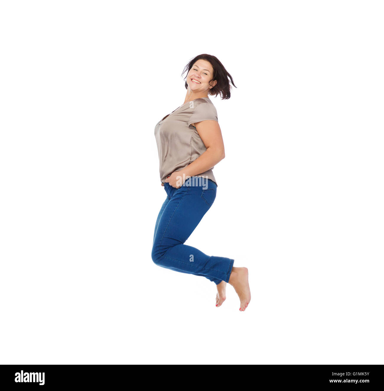 plus Size Frau hoch in die Luft springen glücklich lächelnd Stockfoto