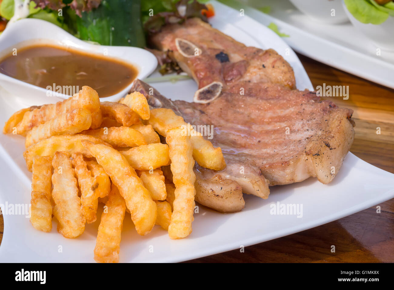 Pommes und Steak Schweinekotelett mit Pilz-Senf-Sauce, Salat. Stockfoto