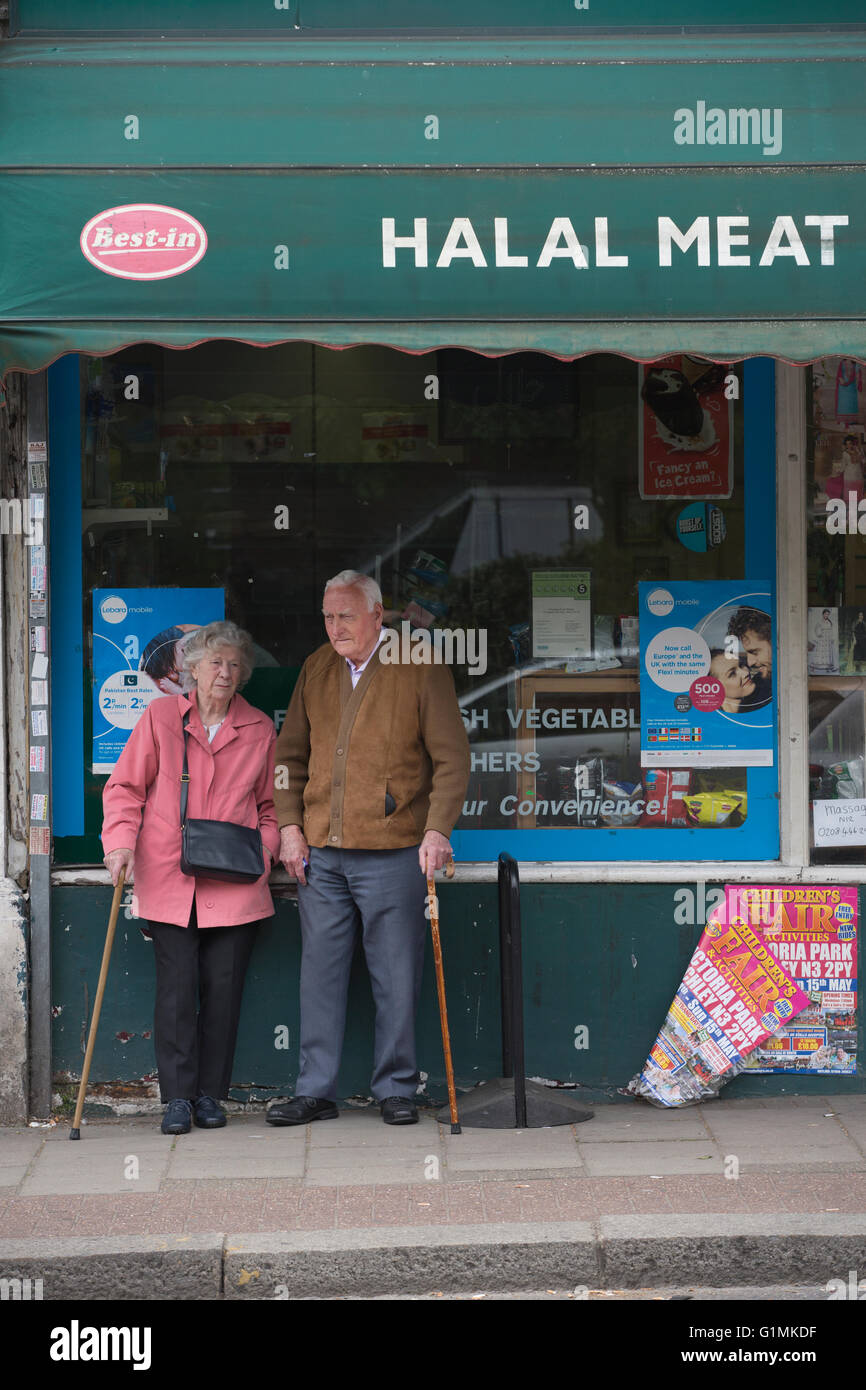 Älteres Ehepaar stand vor einem Halal Fleisch & Geflügel Metzger Geschäft Finchley Central, Nord-London, England, UK Stockfoto