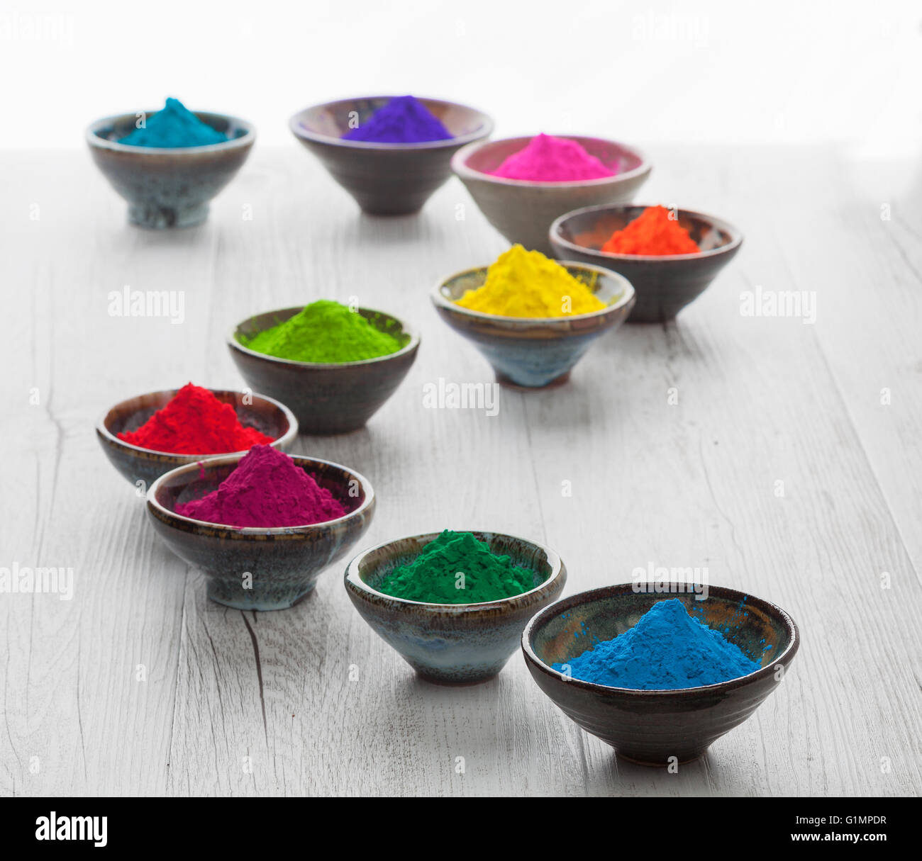 Farbenfrohe Holi-Pulver in Tassen in eine Schlange-Form angeordnet. Geringe Schärfentiefe mit Hintergrundbeleuchtung. Stockfoto