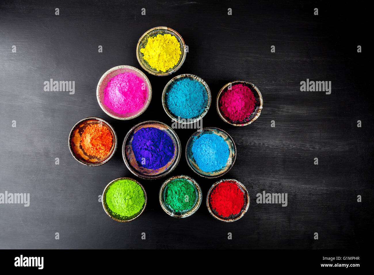 Pulsierenden Holi Pulver in Tassen an Grunge strukturierte Tafel mit textfreiraum gefärbt. Stockfoto