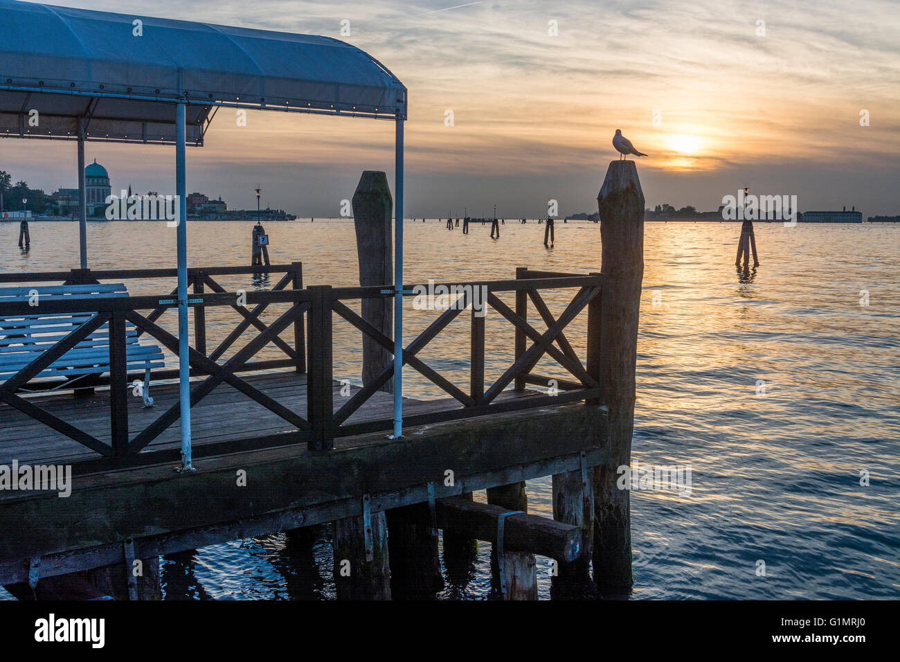 Steg auf der Insel Lido bei Sonnenuntergang, Venedig im Hintergrund Stockfoto