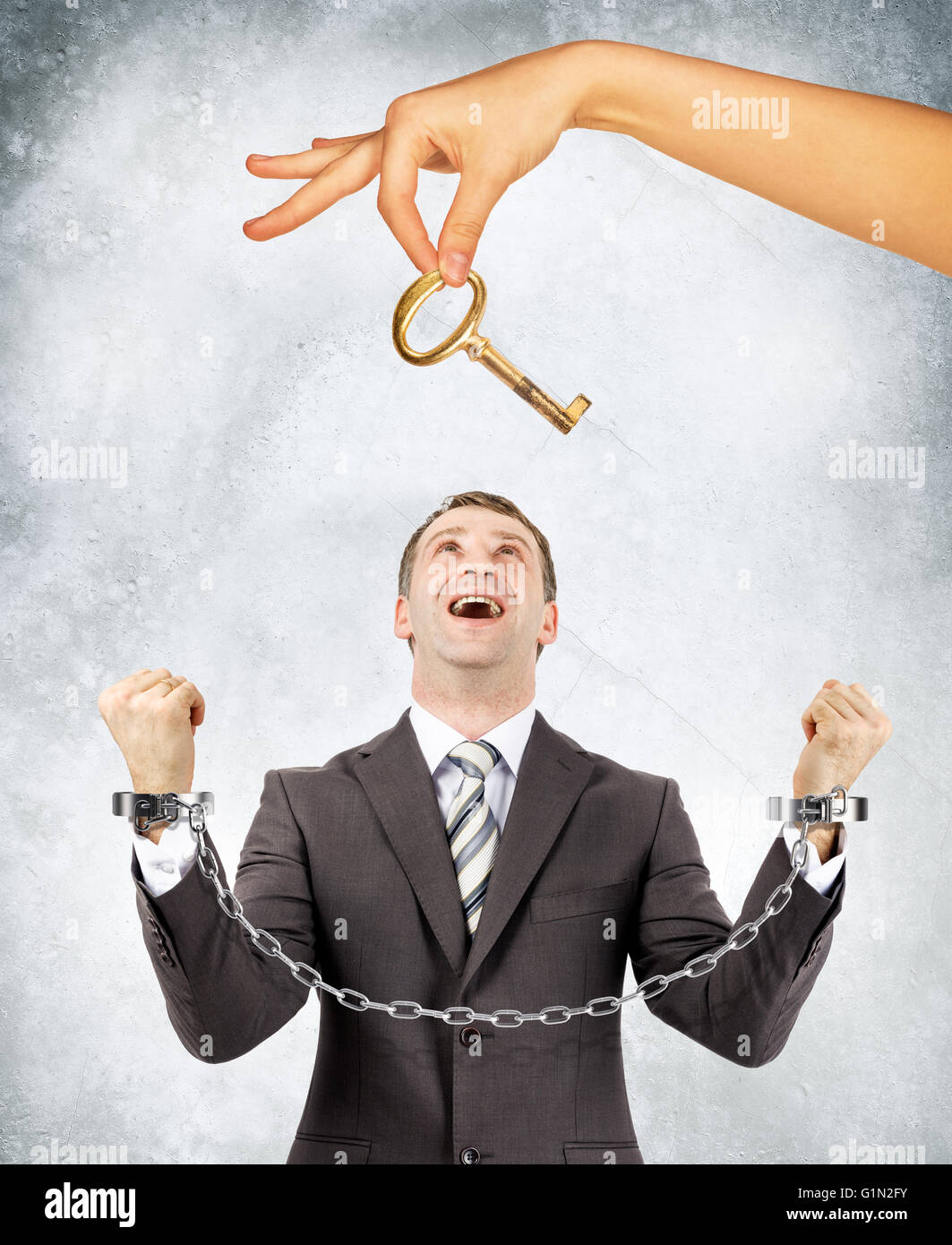 Geschäftsmann in Handschellen und große Hand mit Schlüssel Stockfoto