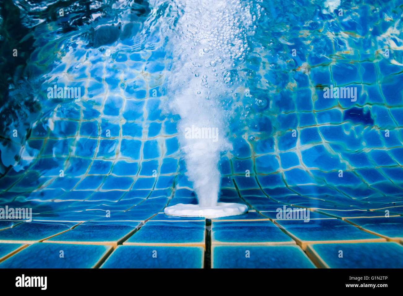 Wasser sprudelt aus dem Loch in der Nähe der Beckenwand. Stockfoto