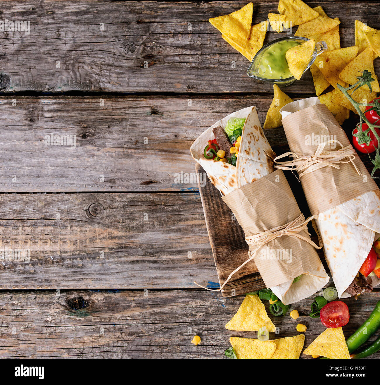 Abendessen im mexikanischen Stil. Zwei tapezierte Tortillas Burrito mit Rindfleisch und Gemüse serviert mit Gemüse, Nachos Chips und guacomole Stockfoto