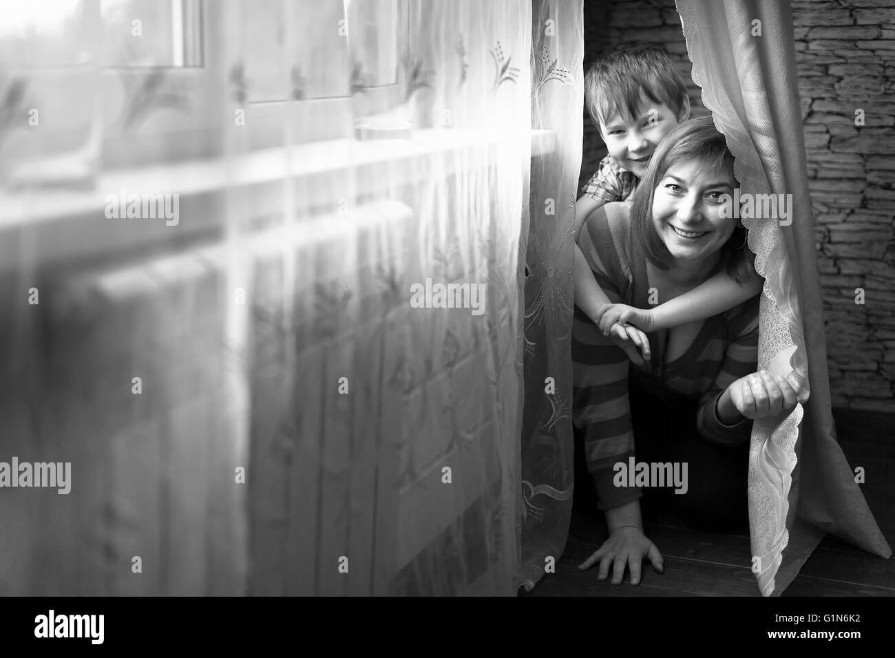 Junge Frau spielt mit seinem kleinen Sohn im Zimmer. Schwarz-weiß-Fotografie. Stockfoto