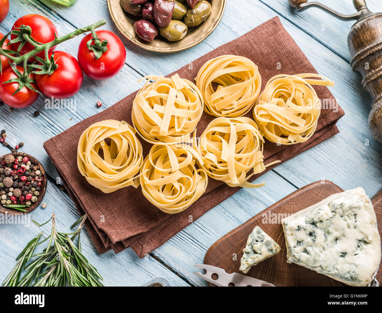 Pasta Zutaten. Cherry-Tomaten, Spaghetti Nudeln, Rosmarin und Gewürze auf dem Holztisch. Stockfoto