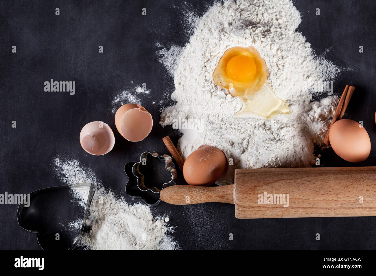 Zutaten wie Eiern, Mehl, Zimt, Anis, Nudelholz, Papier auf Tafel Stockfoto