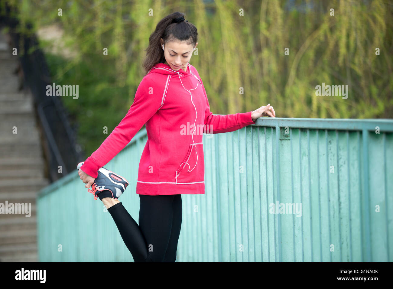 Porträt der sportlichen Frau Dehnübungen im Park vor dem Training zu tun. Sportlerin Läufer Musik hören beim Abrufen Stockfoto
