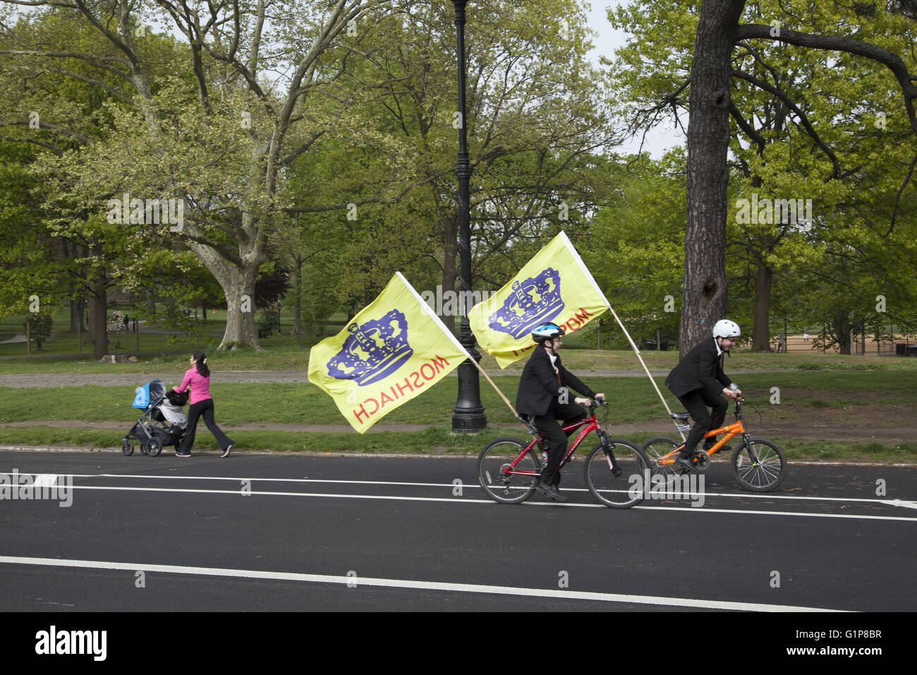 Menschen genießen einen Frühlingstag im Prospect Park, Brooklyn, NY. Jüdische Jungen Fahrrad fahren mit Fahnen loben Messias der Messias. Stockfoto