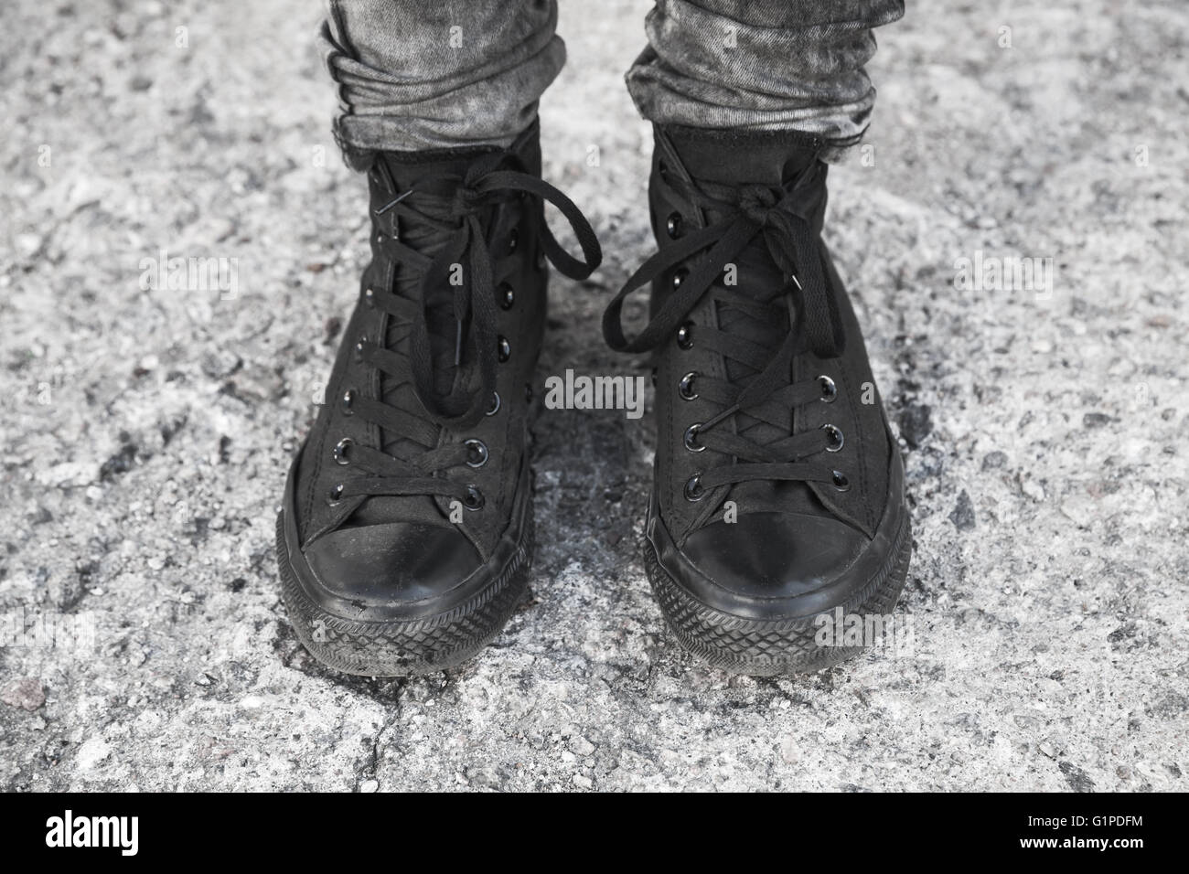 Teenager Füße in schwarzen Detektivkappe auf rauhen Betonboden stehend Stockfoto