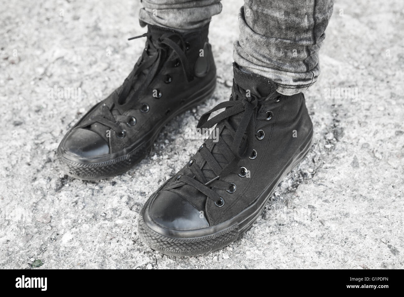 Teenager Füße in schwarzen Detektivkappe auf grauen rauhen Betonboden stehend Stockfoto