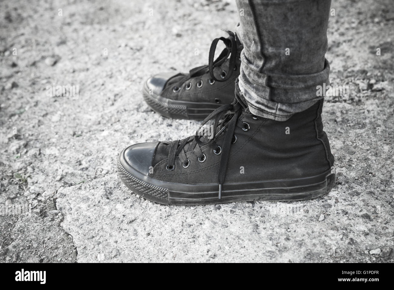 Teenager Füße in schwarzen Detektive und Jeans auf grauen rauhen Betonboden stehend Stockfoto