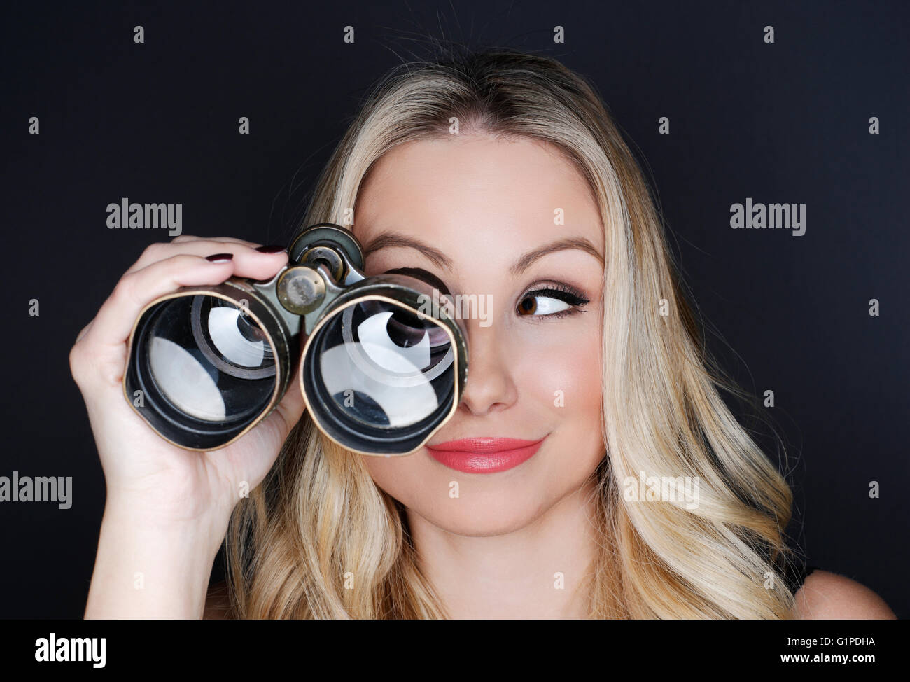 Schöne Blondine sucht alte Fernglas auf schwarzem Hintergrund Stockfoto