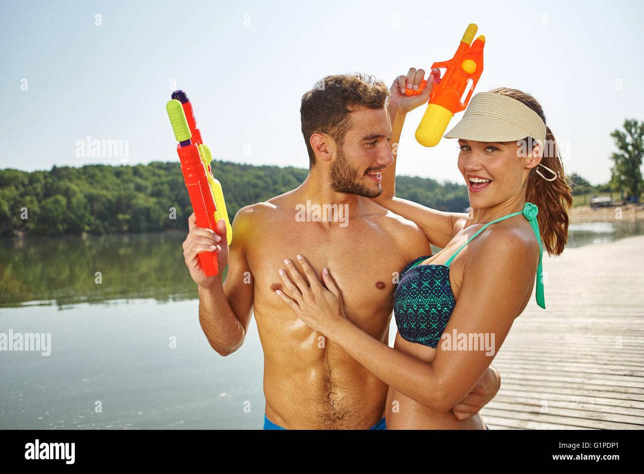 Paar an einem See Spaß mit Spritzpistolen im Sommer Stockfoto