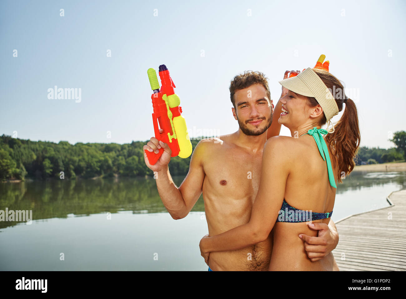 Paar mit Spritzpistolen umarmen einander im Sommer Stockfoto