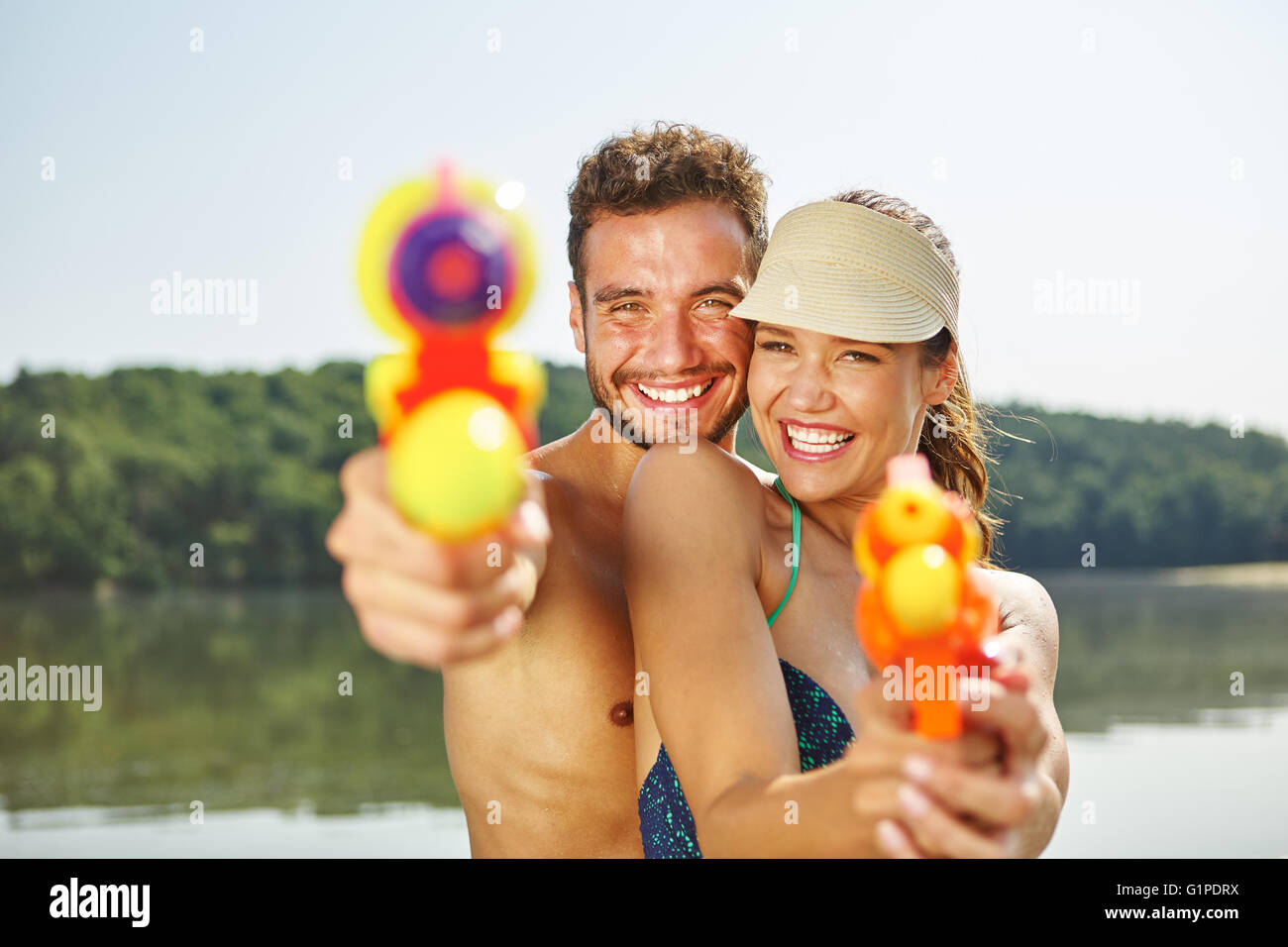 Paar mit dem Ziel mit Wasserpistolen im Sommer und Spaß im Urlaub Stockfoto
