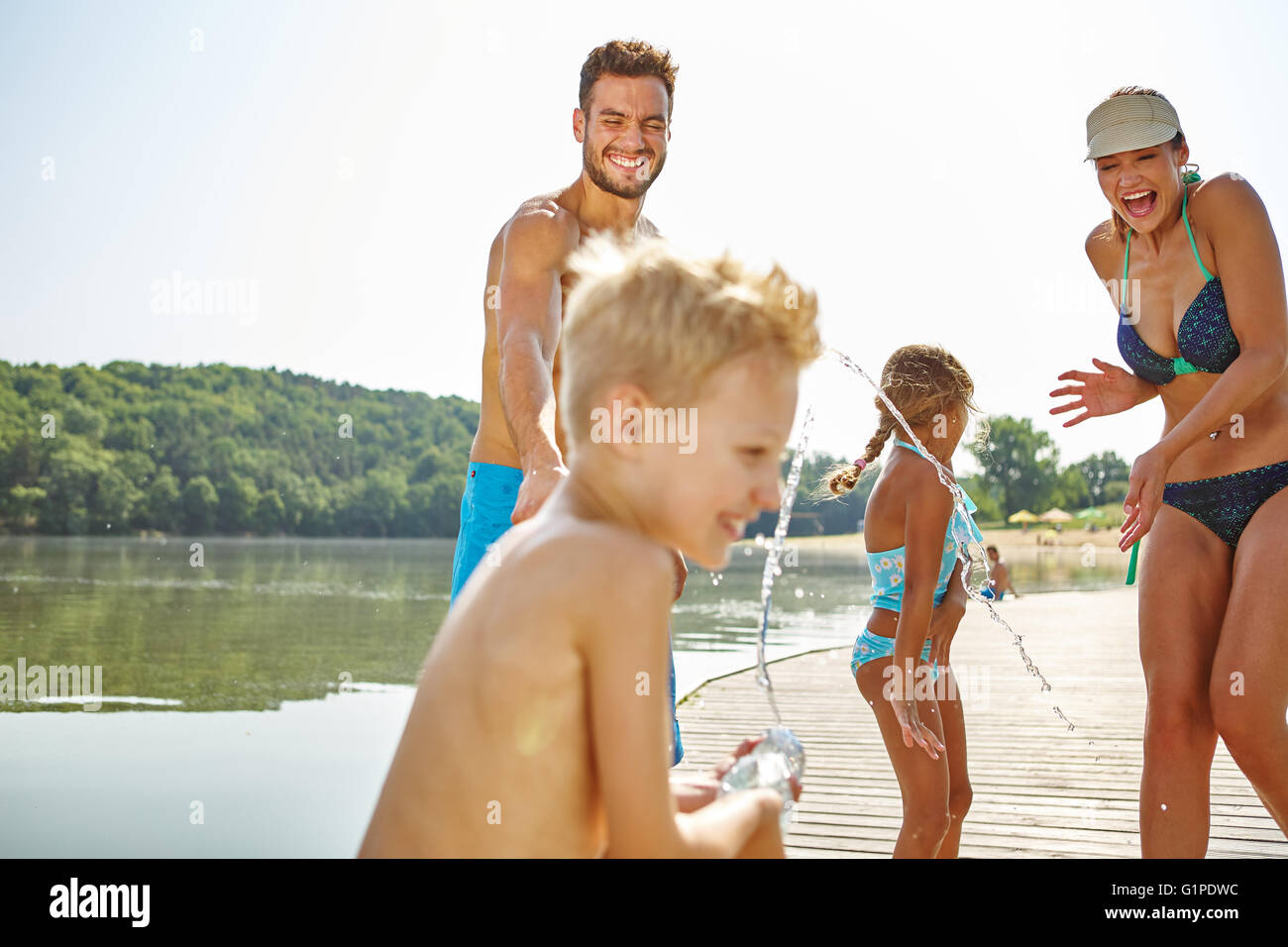 Familie Spray einander an einem See Wasser und Spaß haben Stockfoto