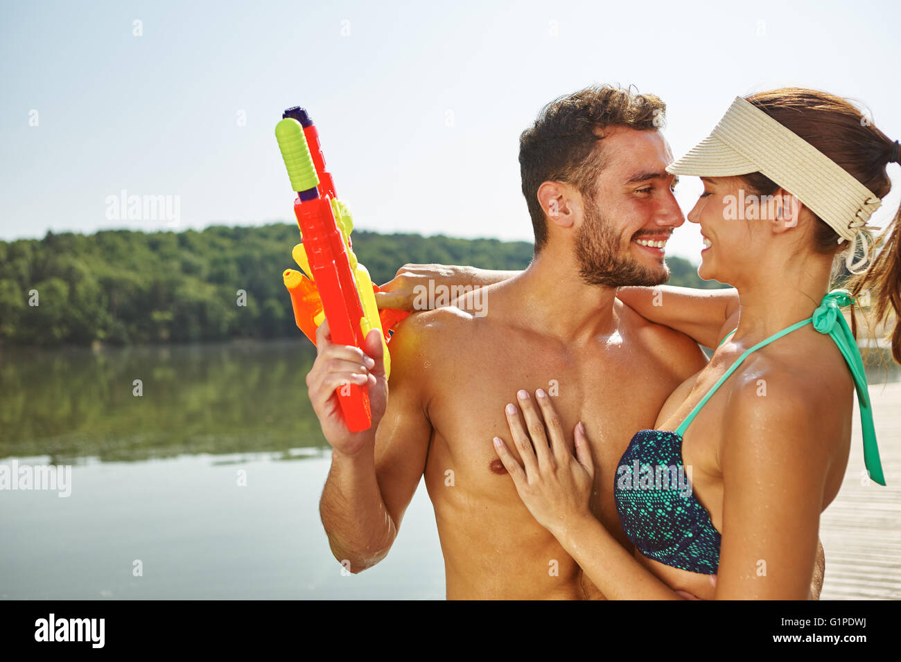 Paar in Liebe umarmt im Sommer an einem See mit Spritzpistolen Stockfoto