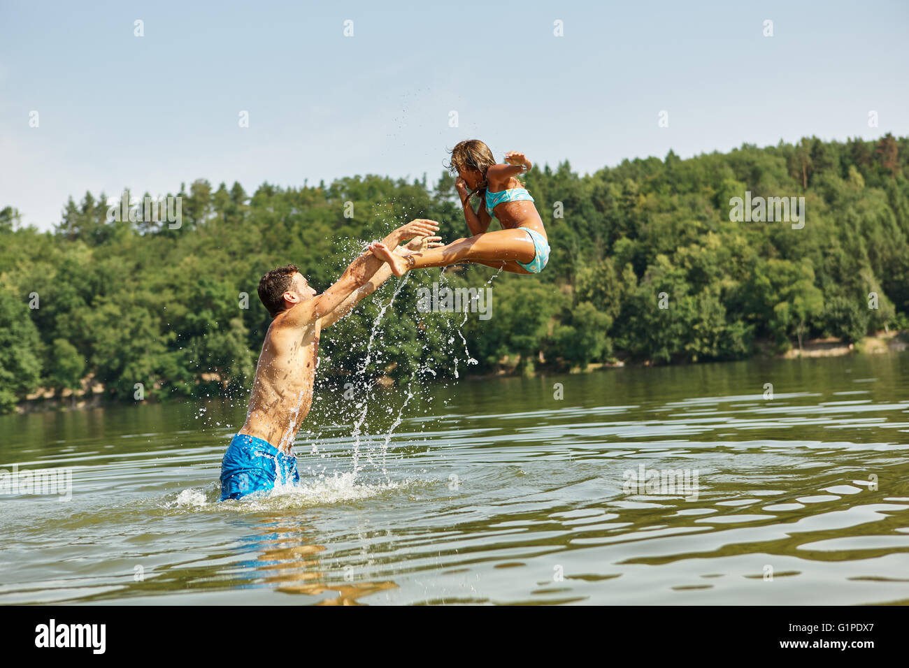 Vater warf Tochter ins Wasser im Sommer und Spaß in den Ferien Stockfoto