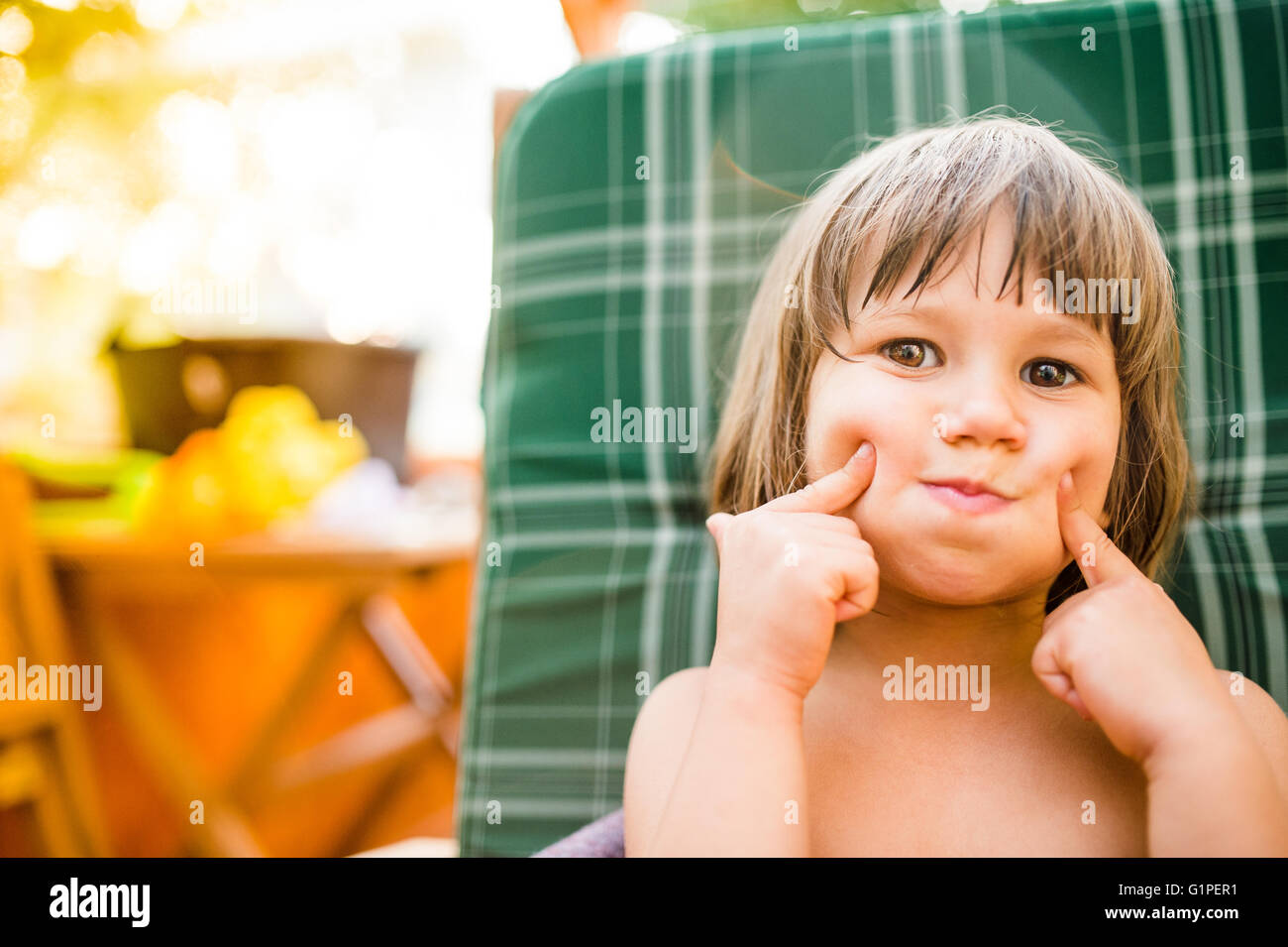 Niedliche kleine Mädchen draußen im Garten hält ihre Wangen Stockfoto