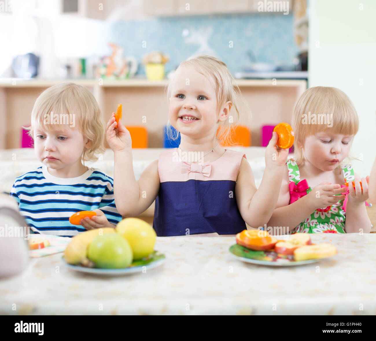 Lustige Kinder essen Orangen in Kindertagesstätte Stockfoto